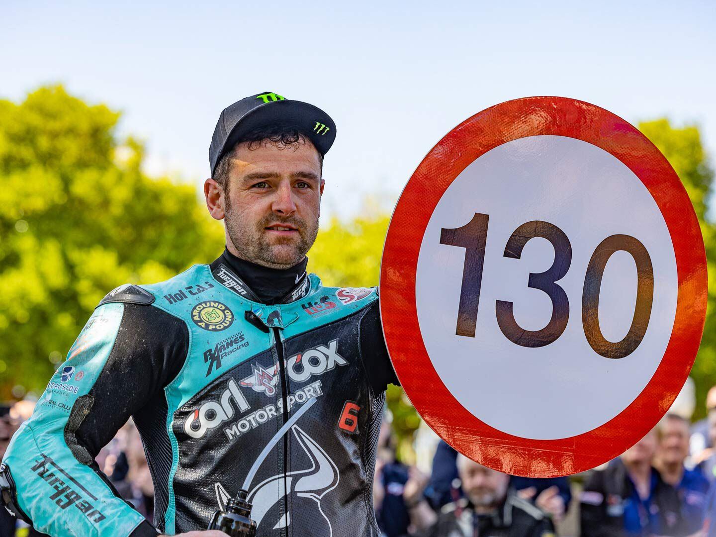 In the winner’s enclosure Michael Dunlop displays his new “Speed Limit” sign for his 130.4 mph record.