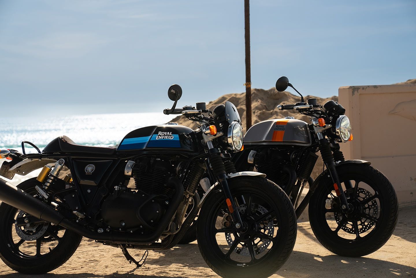 The GT 650 in Slipstream Blue sports Enfield’s small wind deflector above its headlight, while the Apex Grey shows the bike’s stock style.