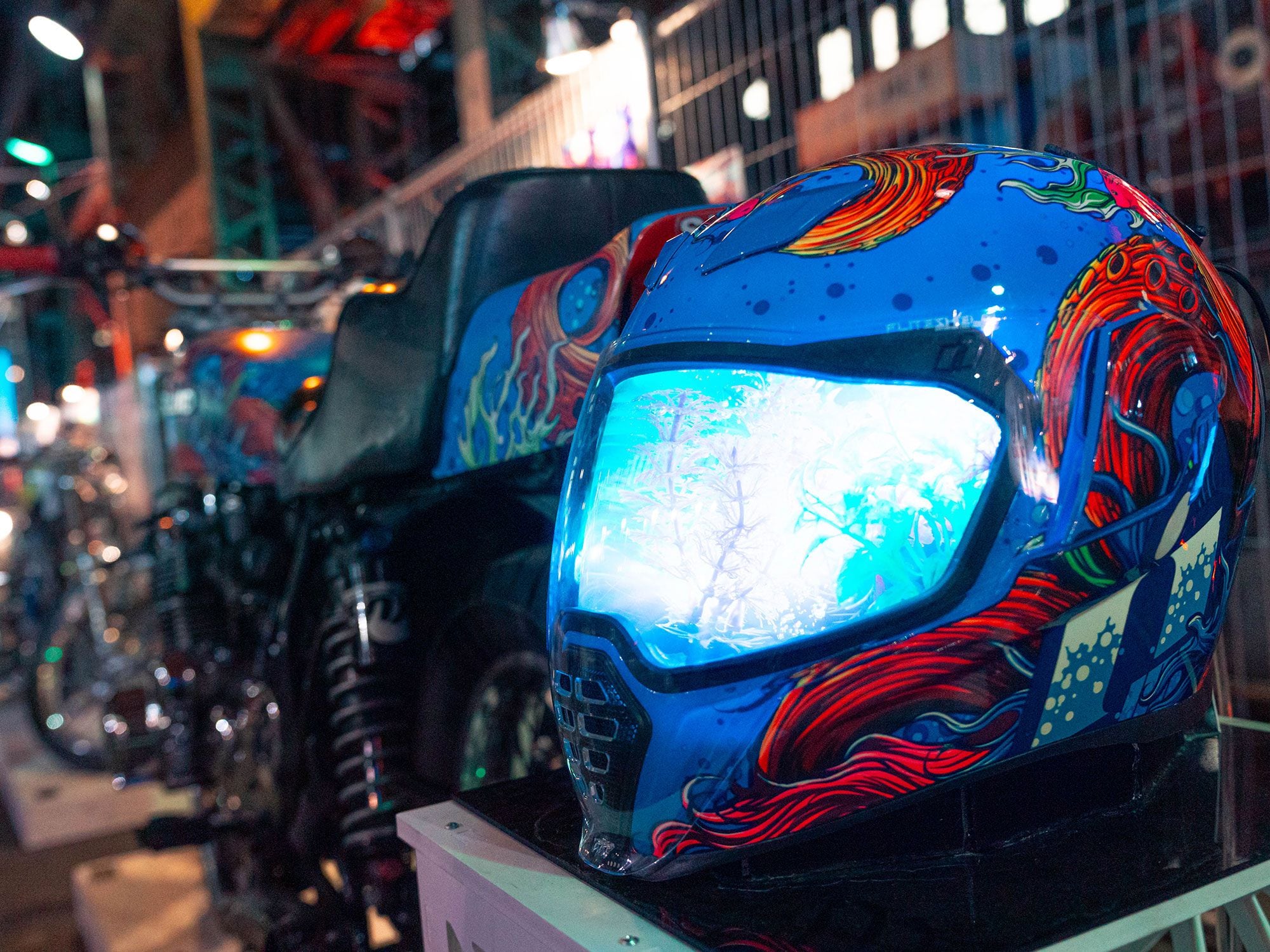 An Icon Airflite helmet lit up like an aquarium and painted to match the custom 1977 Suzuki next to it.