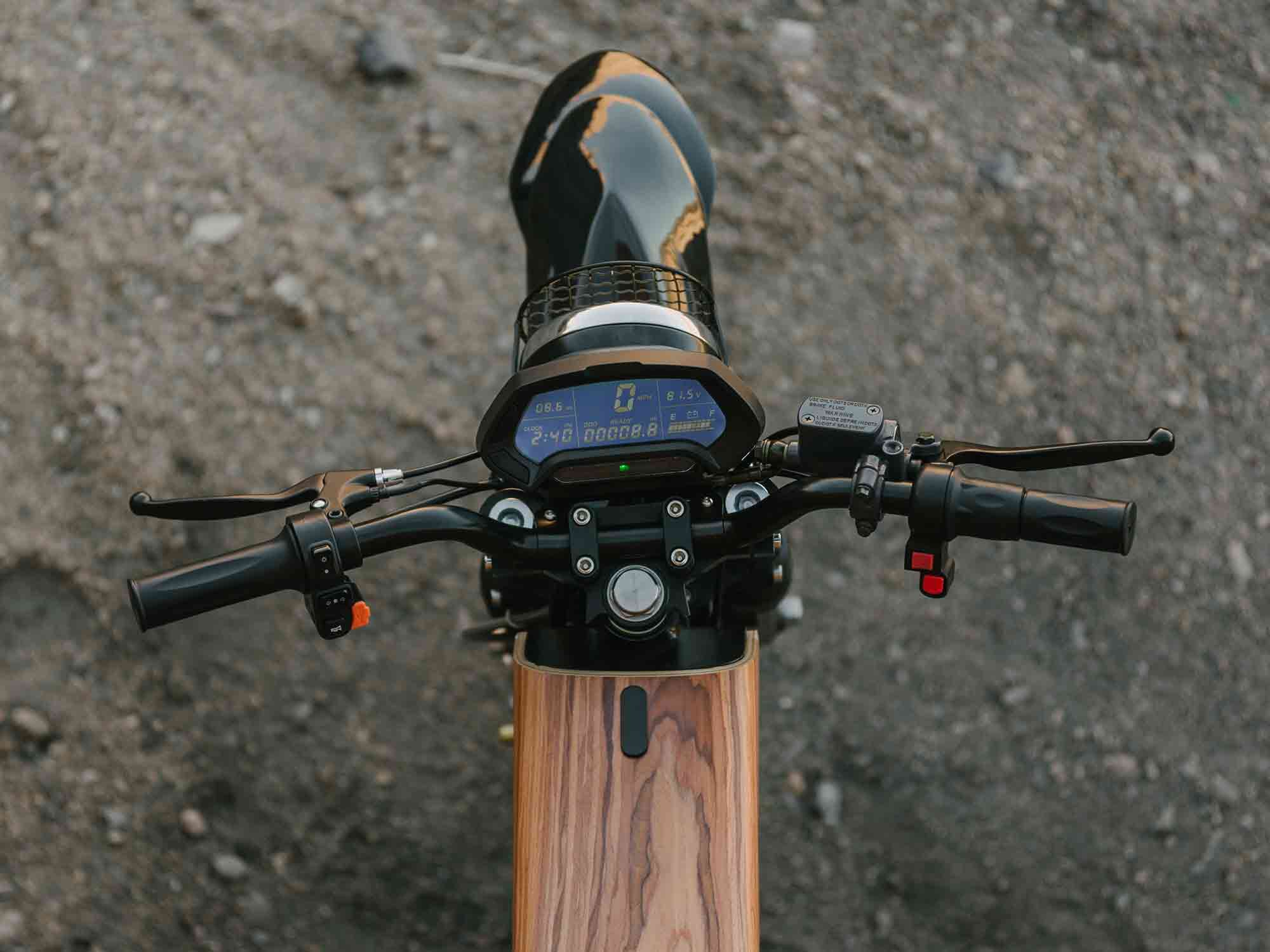 Left-hand controls include blinkers, horn, headlight, and a USB charging port. On the right hand is your throttle, ride mode select toggle, and power switch. The LCD in the middle displays volts, current battery level, mph, time, and odometer.
