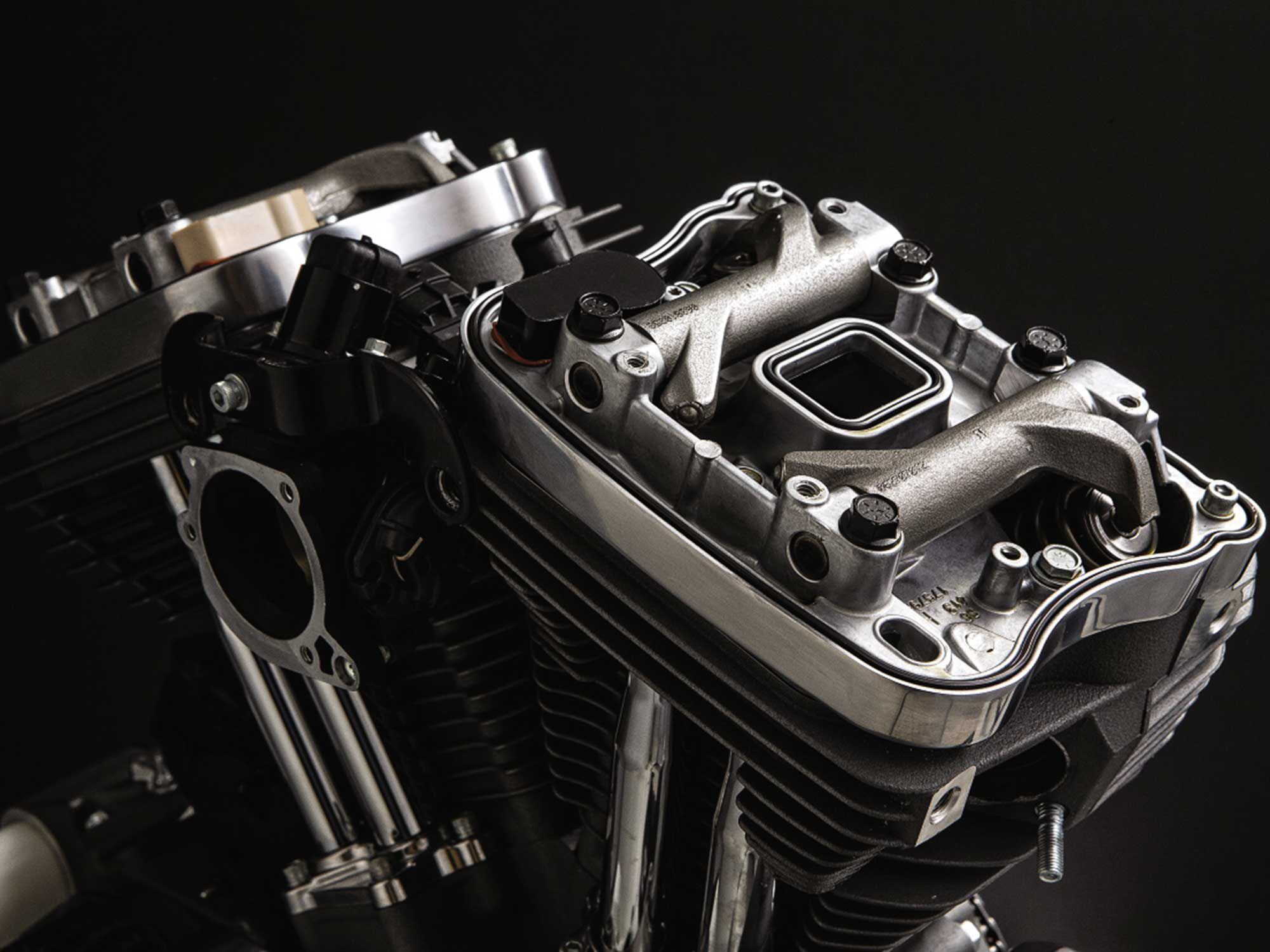 Here we see how construction of the 1200’s top end in layers allows valve service and/or head removal with the engine in the frame (the elements slide out sideways). Here the rocker covers have been removed to reveal the intake and exhaust rocker arms, which transmit the upward thrust of the pushrods into valve movement.