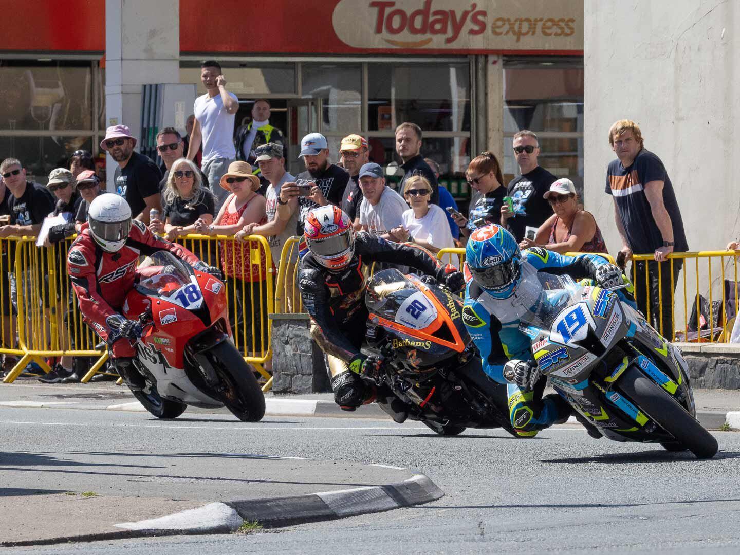 Parliament Square is an amazing spot to watch the TT. Riders come in on a long high-speed straight with some backing into the right turn, then a quick left, and on to May Hill before heading up to the mountain. Manx rider Michael Evans on his Honda CBR600RR, Craig Neve on his Triumph Daytona Street Triple 765 RS, and Shaun Anderson also on a Honda CBR600RR come through in formation.