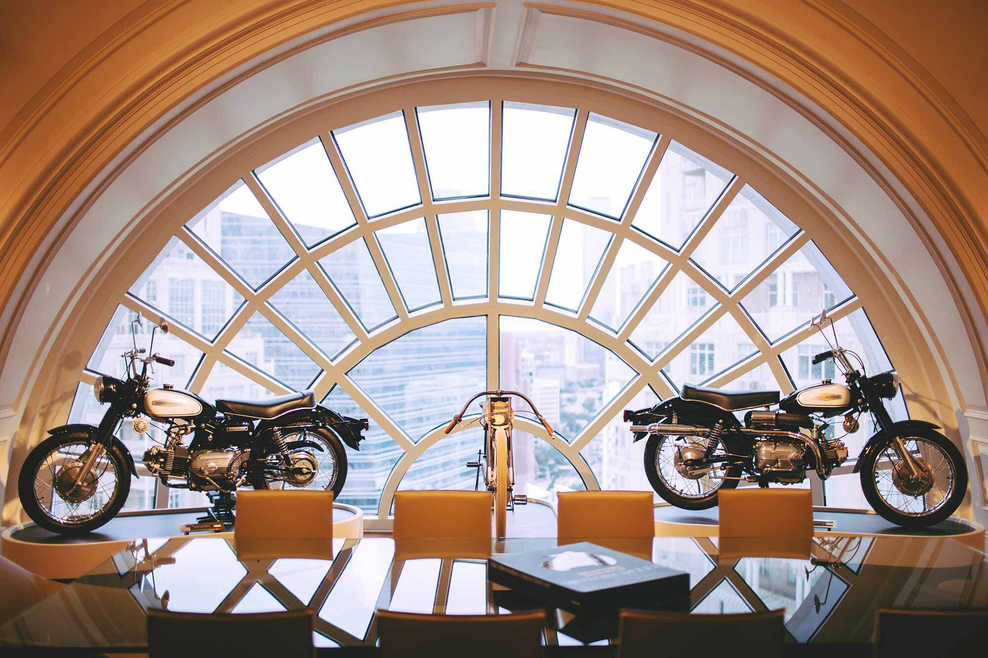 An early American motorcycle flanked by two AMF-era Harley-Davidson Sprint 250s in Bobby’s Dallas office.