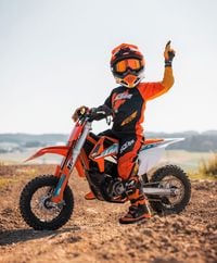 KTM SX-E 3 parked on dirt road with youth rider aboard