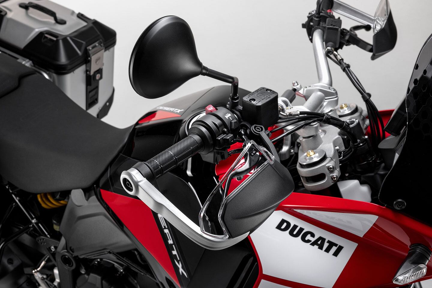 Reinforced hand guards and heated grips as well as a larger aerodynamic touring shield are included, but those sidecases you see in the background look to be accessory options.