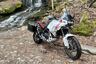 Ducati DesertX outfitted with accessories parked next to waterfall