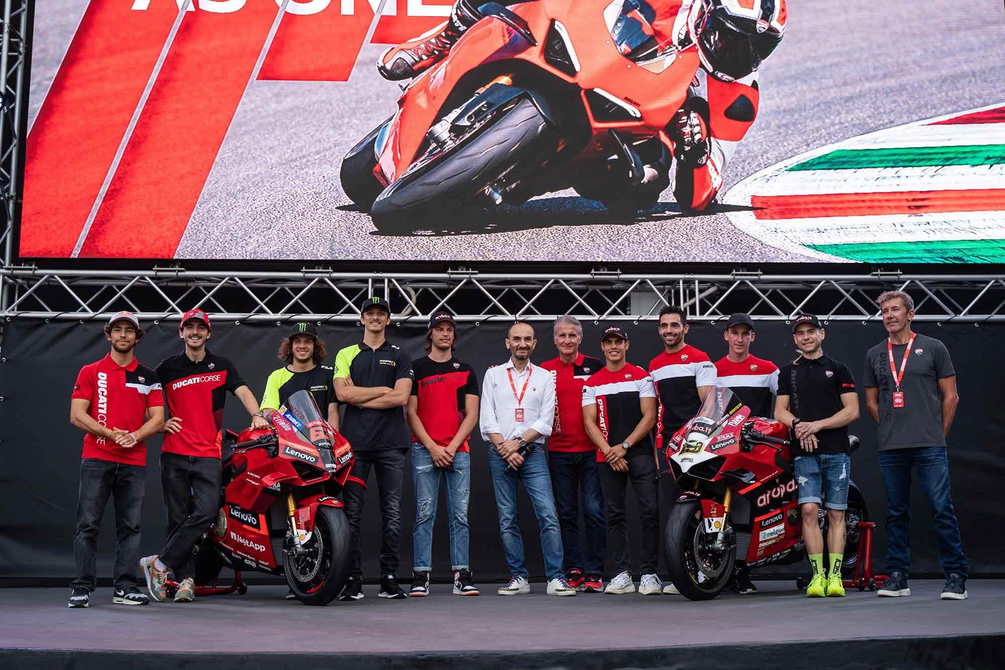 A group of serious Ducati riders: Bastianini, Bagnaia, Bezzecchi, Marini, Bulega, Domenicali, Ciabatti, Rinaldi, Pirro, Oliver Bayliss, Bautista, and Troy Bayliss.