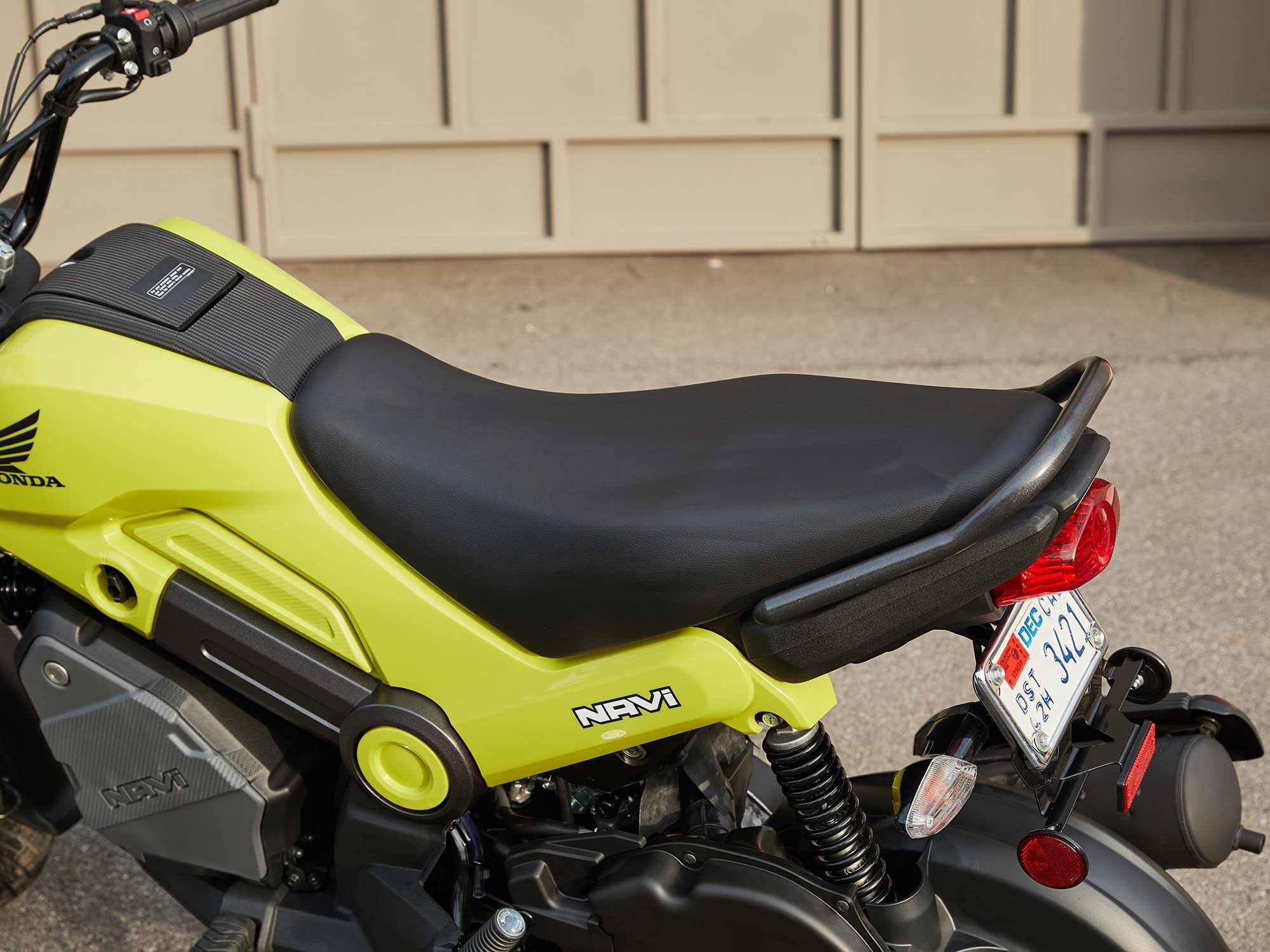 The Navi’s saddle is comfy enough for two, and the single shock does an adequate job of absorbing minor pavement irregularities. The keyed panel behind the steering head accesses the 0.9-gallon fuel tank; note the fuel petcock (remember those?) just above the storage bin.